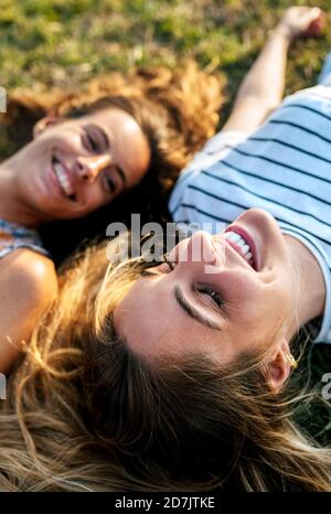 Smiling young woman relaxing with sister on field Stock Photo