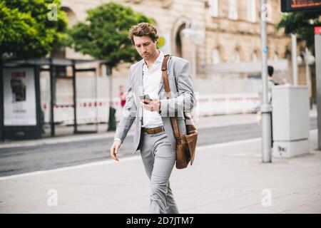 Businessman using mobile phone while walking in city Stock Photo