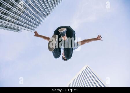 Young man performing parkour against sky in city Stock Photo