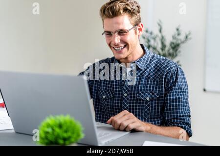 Smiling man using laptop while sitting at office Stock Photo