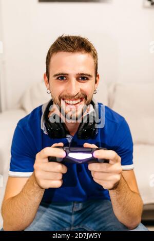 Smiling handsome young man playing video game at home Stock Photo