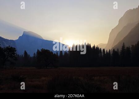 The sun is shown starting to rise over mountains of the Sierra Nevada range in Central California during the early morning. Stock Photo