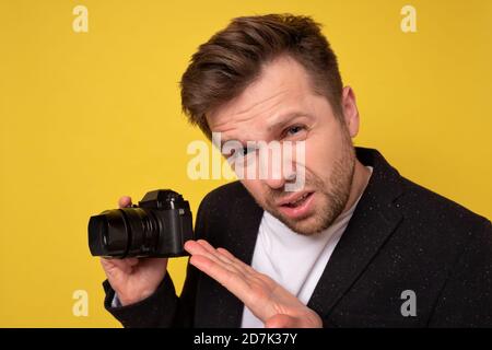 Studio portrait of handsome young man holding photocamera taking photo. Stock Photo
