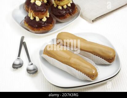 PLATE WITH FRENCH CAKES CALLED CHOCOLATE RELIGIEUSE AND COFFE ECLAIR Stock Photo
