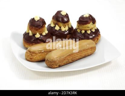 PLATE WITH FRENCH CAKES CALLED CHOCOLATE RELIGIEUSE AND COFFE ECLAIR Stock Photo