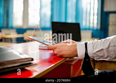 Professor in classroom using laptop and digital tablet Stock Photo