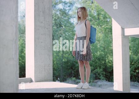 Woman with a backpack standing in the forest on a concrete staircase. Stock Photo