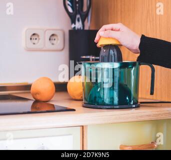 woman's hand squeezing oranges in the kitchen Stock Photo
