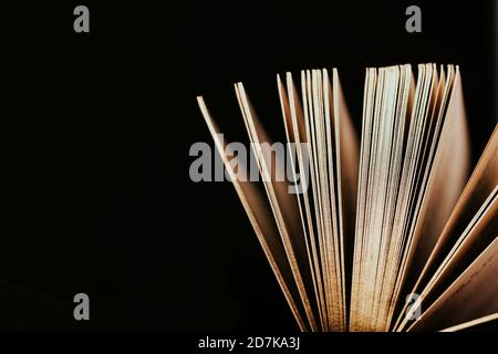 Opened old book with gold pages on a black background, copy space Stock Photo