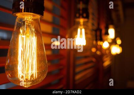 Golden shining antique Edison style bulbs in the dark. Lighting decor concept. Vintage light bulb. Blur background of retro lights Stock Photo