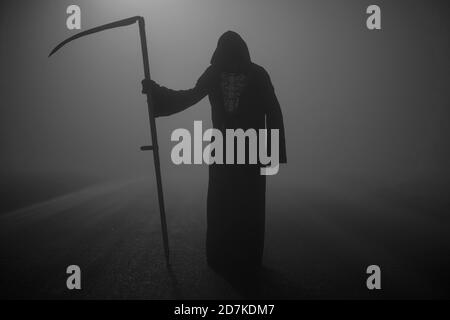 Death grim Reaper skeleton wearing a black robe and wielding a scythe, Memento Mori, Coronavirus, Epidemic and Pandemic Time Stock Photo