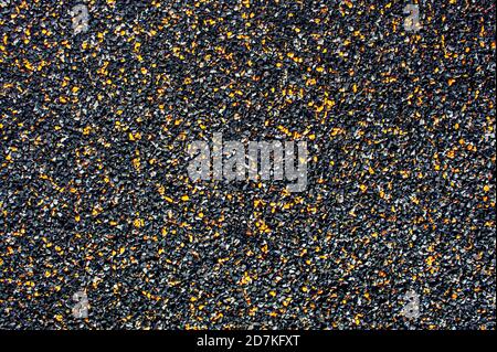 Dark abstract background from small stone chips of black and orange colors. Copy space. Ground coverage Stock Photo