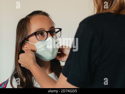 Mother adjusting the mask to her kid before she goes to school Stock Photo