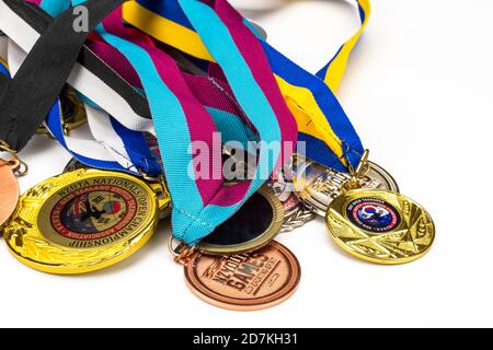 Plenty of shiny sport medals on different colorful ribbons isolated on white background. Flat horizontal view. Stock Photo
