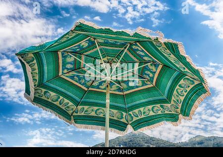 Decorated green beach umbrella as seen from the ground against the background of a light sky Stock Photo