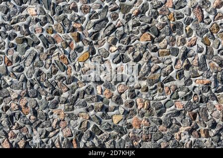 Wall decorated lot of small stones, abstract texture background. Many granite stones in cement or concrete surface, pattern on modern building exterio Stock Photo