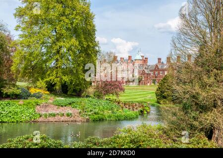 Sandringham House seen across the ornamental gardens and part of the lake in the grounds.