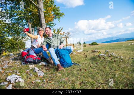 Cheerful young couple taking a selfie outdoor during the travel in the mountains Stock Photo
