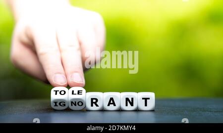 Hand turns dice and changes the  word 'ignorant' to 'tolerant'. Stock Photo