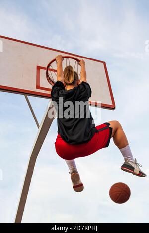 Females playing basketball on street court. Woman streetball player making slam dunk in a basketball game. Stock Photo