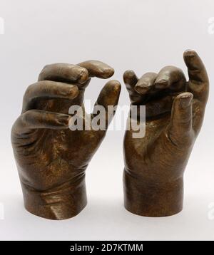 Photo of Children's hands sculptures cast in bronze and strongly lit against a white background Stock Photo