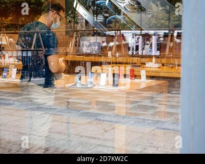 Paris, France - Oct 23, 2020: View from the street of Apple Genius employee looking at new iPhone 12 and iPhone 12 Pro on display during launch day in Apple Store. Latest 5G smartphones go on sale worldwide. Stock Photo