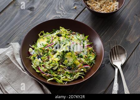 Salad from brussels sprouts with radish, raisins and sprouts of wheat. Healthy diet detox food. On a wooden background in a rustic style Stock Photo