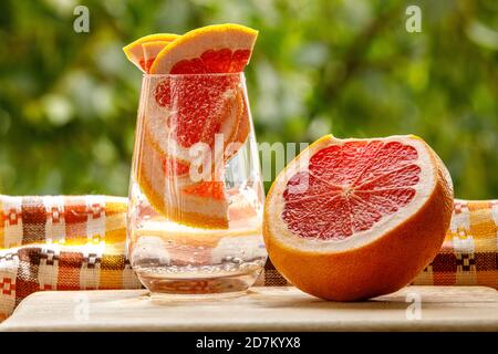A glass of water with grapefruit in the garden background. Stock Photo
