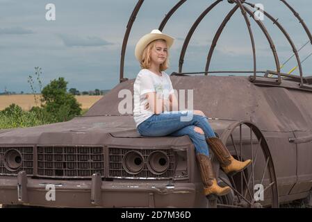 A teenage girl poses on a car at Carhenge, a roadsidde attraction in Nebraska. Photo by Liz Roll Stock Photo