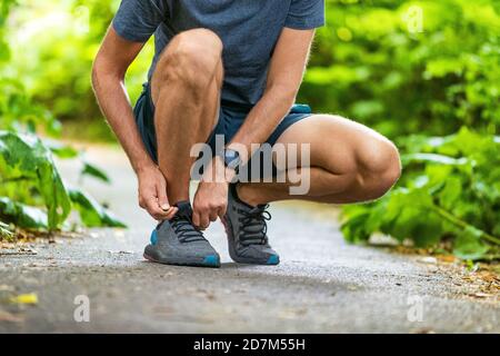Running shoes sports smartwatch man tying shoe laces. Male fitness runner getting ready to jog in spring autumn jogging outdoor wearing technology Stock Photo
