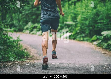 Runner man athlete jogging in city run on park path running view from back summer outdoor green forest Stock Photo