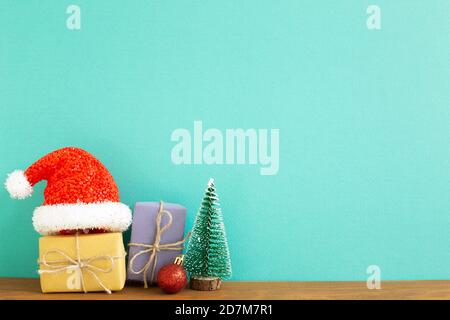 Christmas concept. Gift boxes with fir tree, bauble, santa claus hat on wooden table with green background Stock Photo