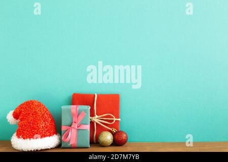 Christmas concept. Gift boxes with baubles, santa claus hat on wooden table with green background Stock Photo