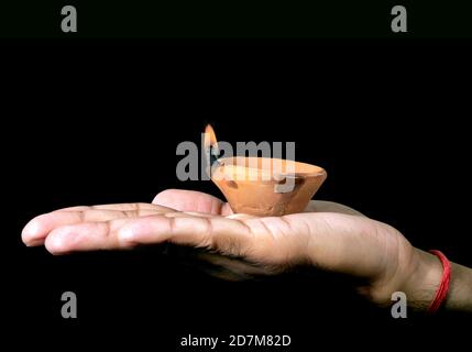 Diwali or deepawali photo with male holding oil lamp or diya during festival of light with copy space isolated on black background. Stock Photo