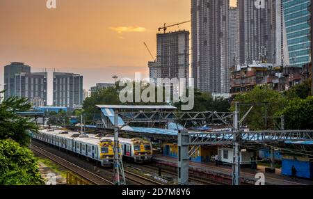 MUMBAI, INDIA - October 17, 2020 : Mumbai Suburban Railway, one of the busiest commuter rail systems in the world. Mumbai Cityscape at sunset with sky Stock Photo