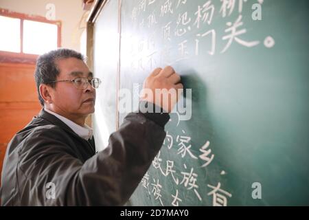 (201024) -- BEIJING, Oct. 24, 2020 (Xinhua) -- Wang Jianlin gives a lesson in Changshan School, Huining County, northwest China's Gansu Province, Oct. 22, 2020. 57-year-old Wang Jianlin is the only teacher in Changshan School. In 1987, Wang was called back from Lanzhou to replace his ill brother as a local school teacher and look after his students. In 1997, an acute eye disease caught Wang, and his eyes swelled and could not see the light. He did not go to the doctor in time, because he did not want to suspend his class. The illness became more and more serious, and by the time he got treat Stock Photo