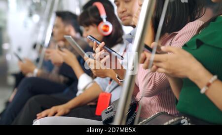 Young people using mobile phone in public underground train . Urban city lifestyle and commuting in Asia concept . Stock Photo