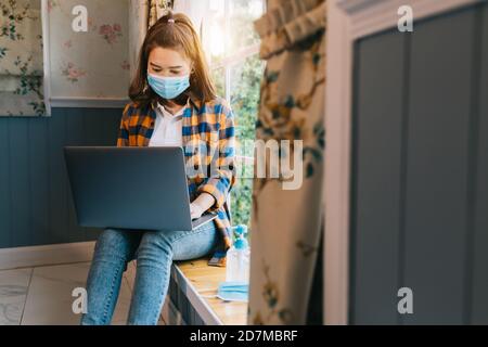 Asian female freelancer wear a mask working on project making internet researchers analyzing data using laptop computer and wireless connection to 5G Stock Photo