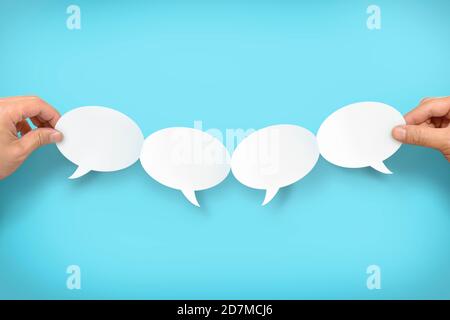 Two hands holding up four speech bubbles Stock Photo