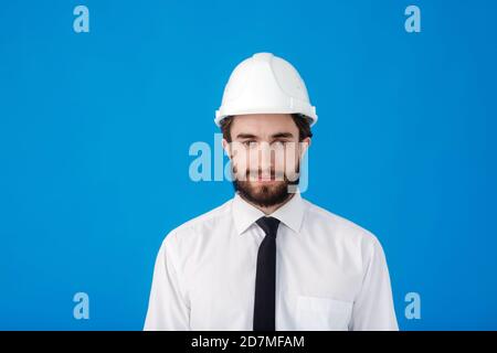 Young bearded civil engineer on blue isolated background. Studio portrait of the architect close - up Stock Photo