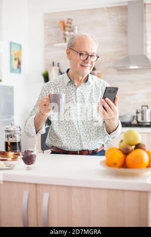 Senior man chatting online via modern smartphone. Elderly person using internet online chat technology video webcam making a video call connection camera communication conference call Stock Photo