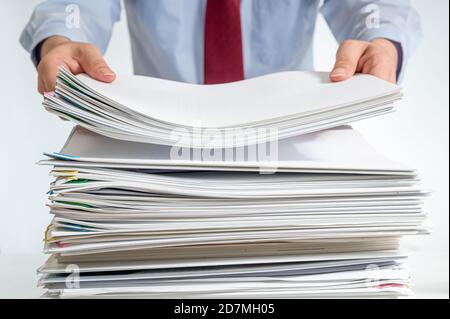 A stacked document or report and the hand of a businessman holding it. Stock Photo