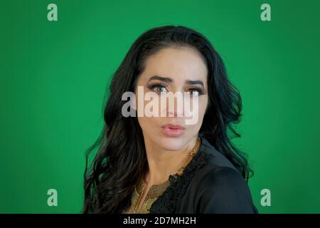 Attractive Hispanic woman posing for the camera in front of a green background Stock Photo