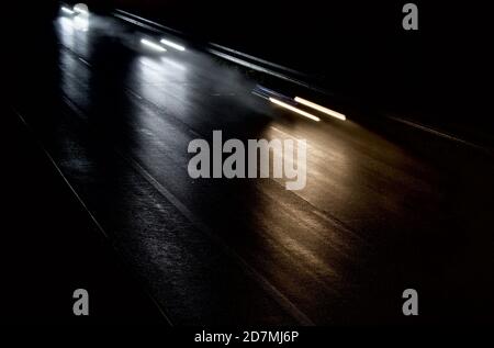 cars moving fast on a  dark and wet highway Stock Photo