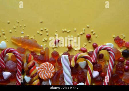 candies with jelly and sugar. colorful array of different childs sweets and treats on yellow background. red marmalade in the shape of a heart with a Stock Photo