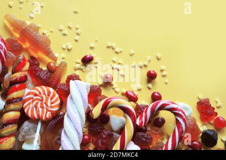 candies with jelly and sugar. colorful array of different childs sweets and treats on yellow background. red marmalade in the shape of a heart with a Stock Photo