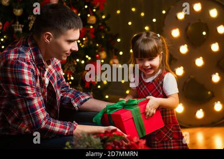 Cute little girl is happy New Year gifts. Father with daughter in magic night. Happy family opening presents and having fun on Christmas Eve Stock Photo