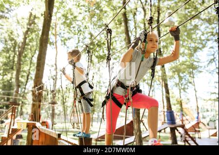 Little brother and sister climbs in rope park Stock Photo