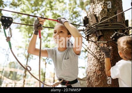 Little kids climbs in rope park, playground Stock Photo