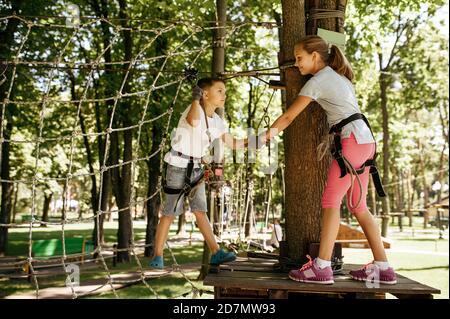 Little kids climbs on net in rope park, playground Stock Photo